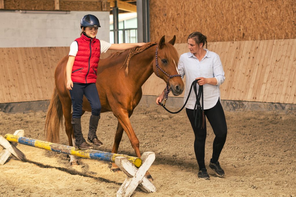 Ergotherapeutin führt Pferd während Kind balanciert