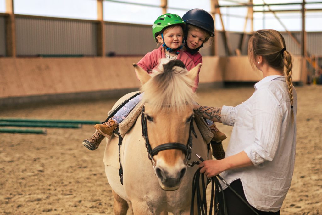 Zwei Kinder machen Gleichgewichtsübungen bei der Pferdegestützten Förderung