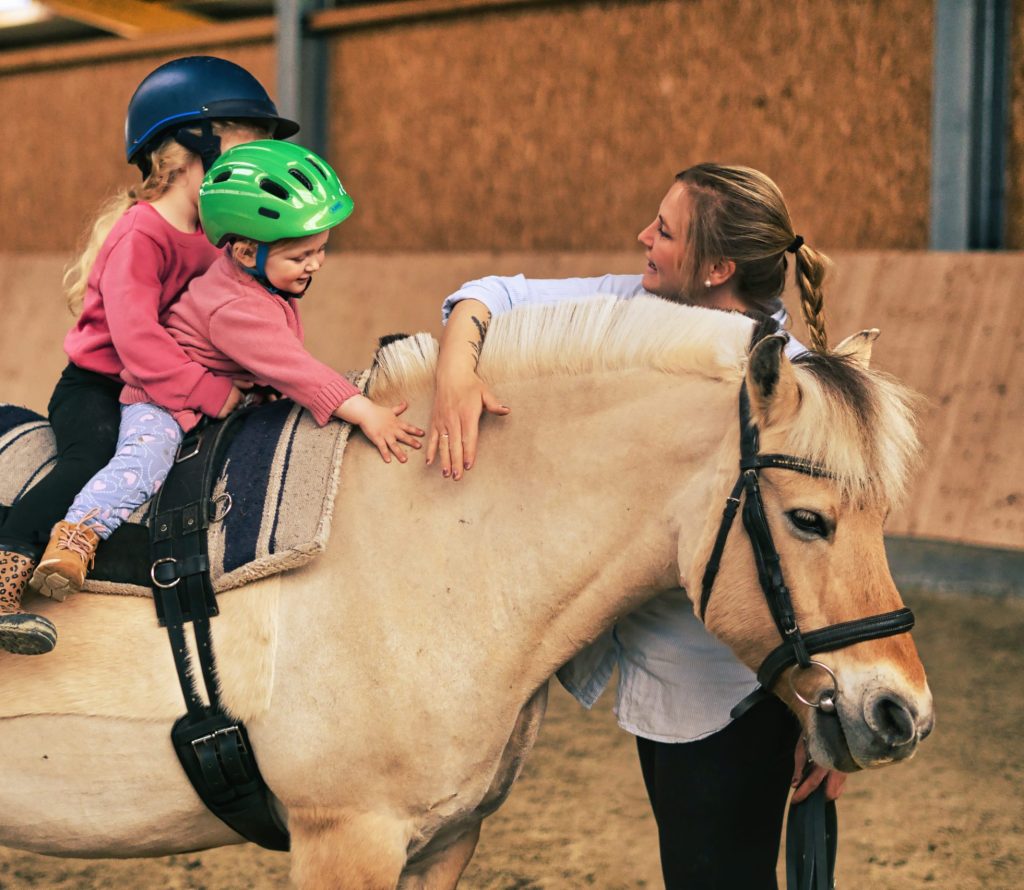 Kind streichelt das Pferd während der Reittherapie