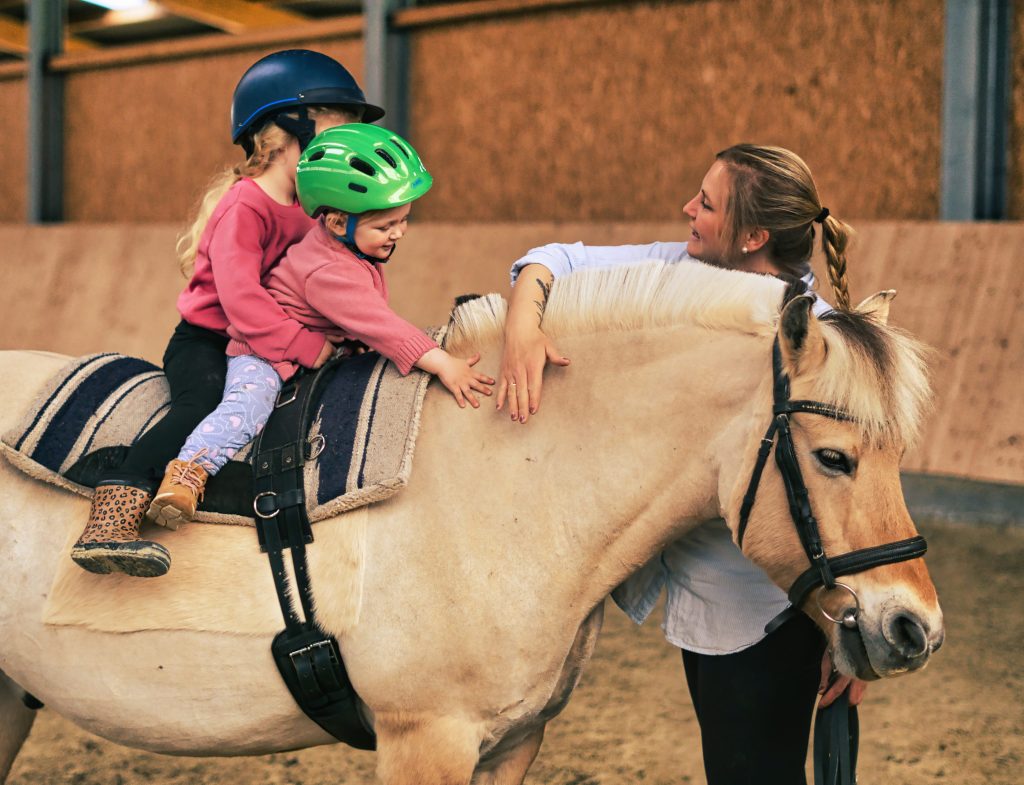 Kind streichelt das Pferd während der Reittherapie